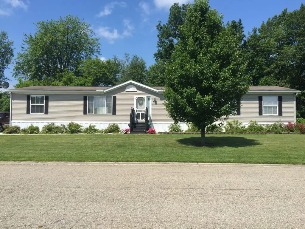 affordable homes for sale in Morrice, michigan. Mobile home with a nice green lawn a tree at Morrice Meadows.