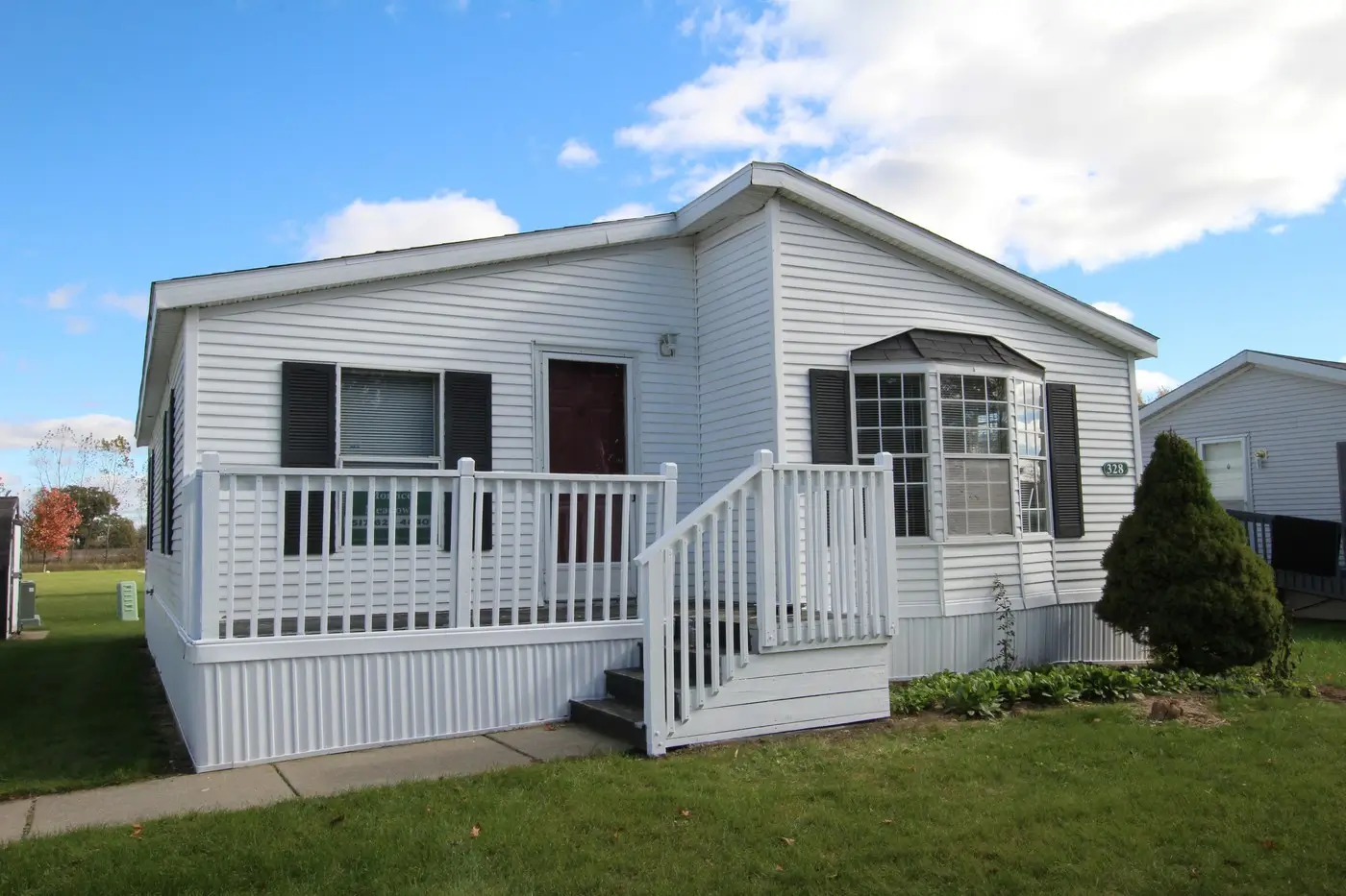White manufactured home with dark green shutters in Morrice, MI.
